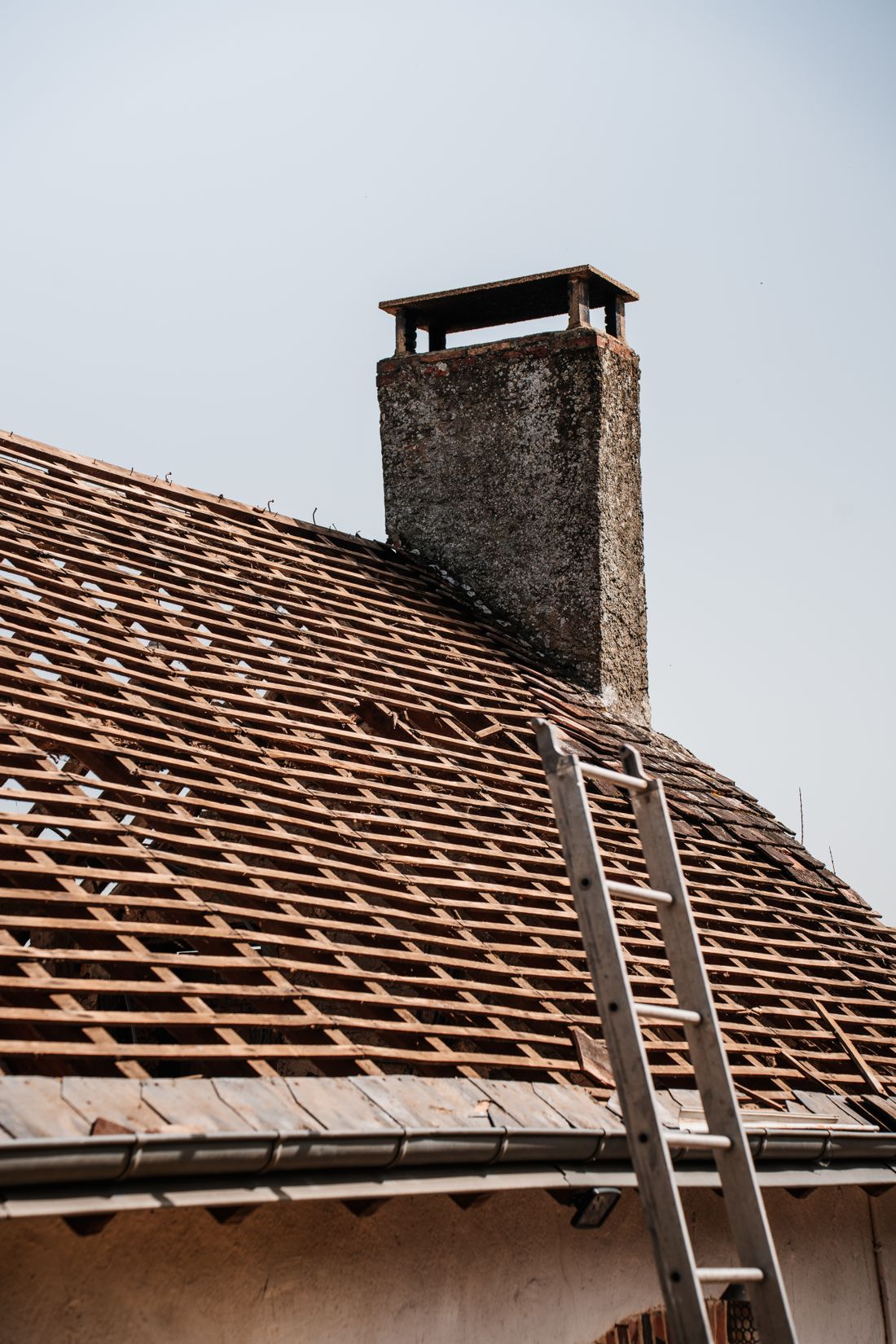 Toiture en rénovation, tuiles déposées autour de la cheminée